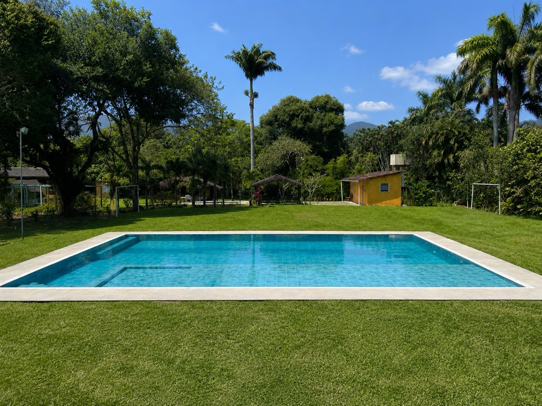Piscina retangular de 140 m² vista do gramado